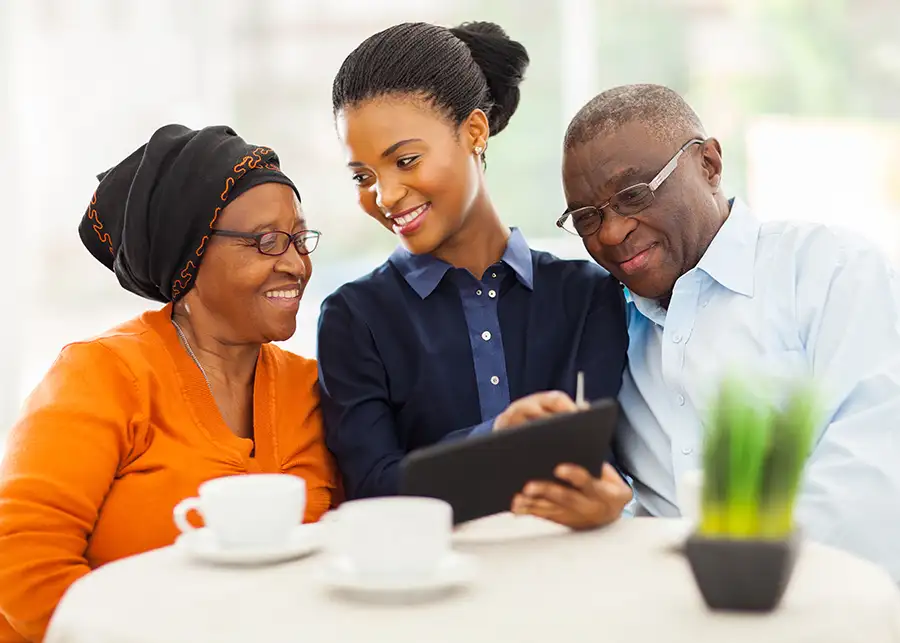 Elderly healthcare insurance agent explaining coverage and mobile application for the benefit of elderly couple clients - African American couple - St. Charles, MO